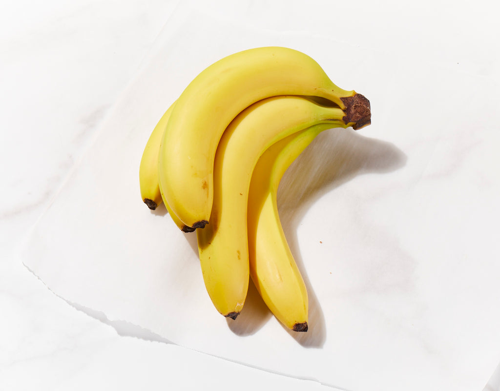 A bunch of ripe bananas resting on a white, marble-like surface.